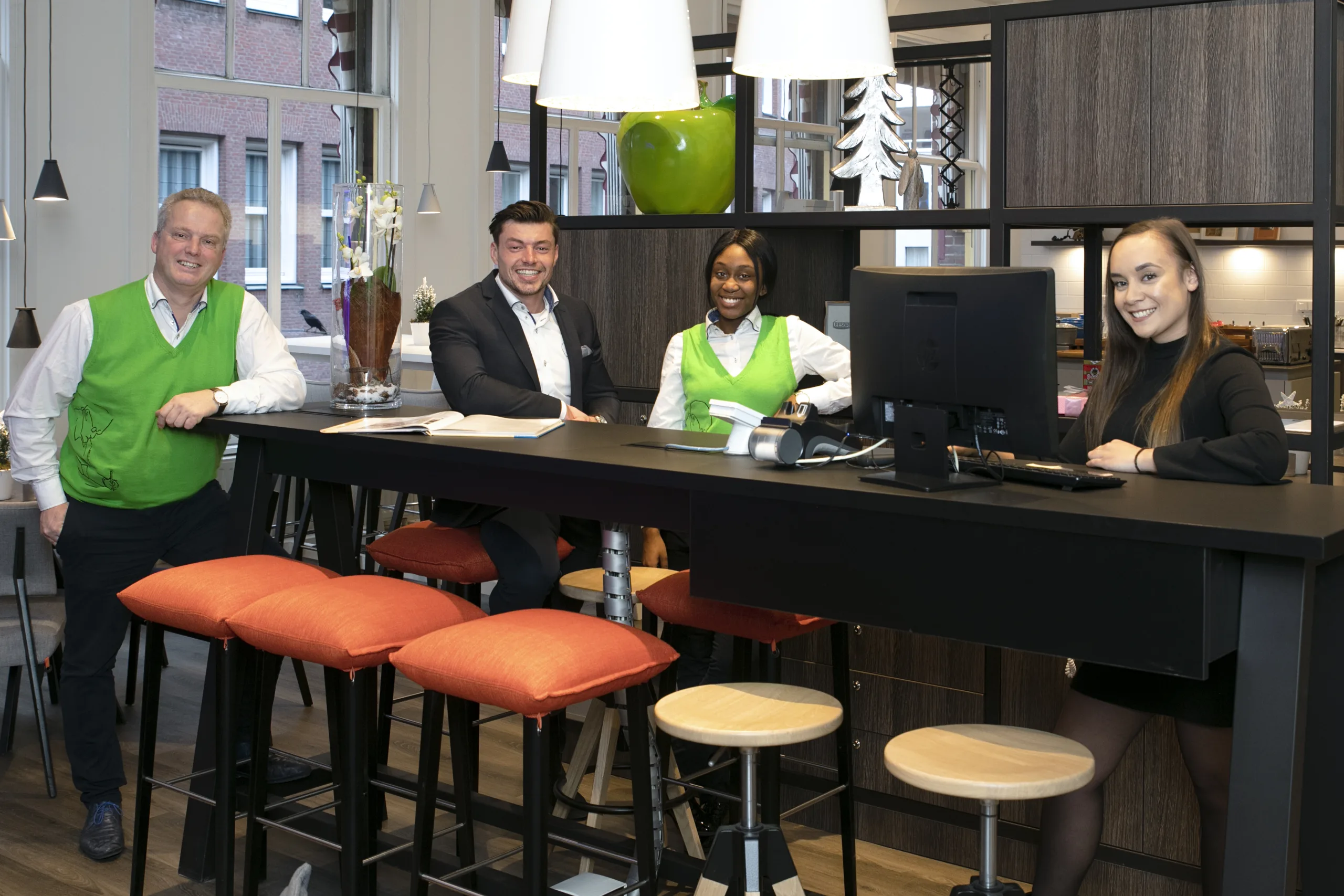 Team van IBIS Styles Den Haag aan de receptietafel in groene spencers en bedrijfskleding van Dutch'n Decent